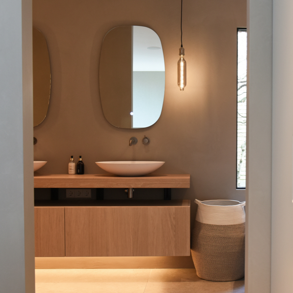 Een houten badkamer met twee houten wastafels, sfeervol belicht