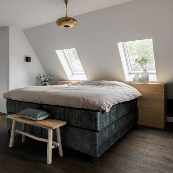 Een slaapkamer met houten vloer en een boxspring bed